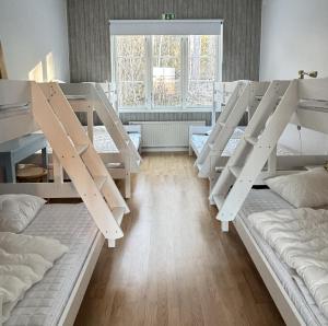 a room with three bunk beds and a window at Haraldsgården Vandrarhem in Blidö