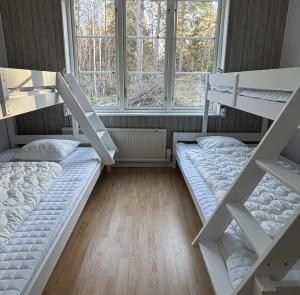 two bunk beds in a room with two windows at Haraldsgården Vandrarhem in Blidö