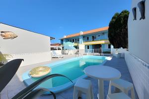 a patio with a pool and a table and chairs at Condomínio Villa do Oceano in Garopaba