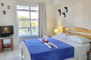 a bedroom with a bed with a blue blanket and a window at Condomínio Villa do Oceano in Garopaba +40 photos