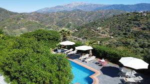 a swimming pool with umbrellas and a view of mountains at Sobremesa Boutique in Sayalonga