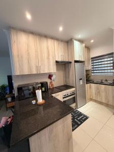 a kitchen with wooden cabinets and a black counter top at Demmys Comfort in Cape Town