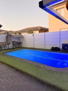 a blue swimming pool in front of a house at Demmys Comfort in Cape Town