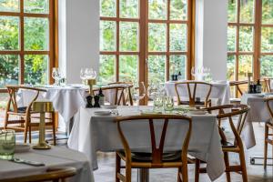 a dining room with white tables and chairs and windows at Gl Skovridergaard in Silkeborg