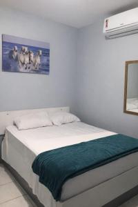 a bedroom with a white bed with a painting on the wall at Pousada Madre De Deus in Brejo da Madre de Deus