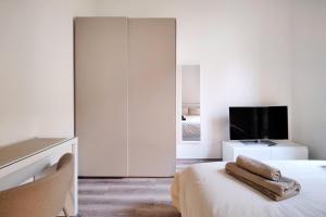 a white bedroom with a bed and a tv at Otto Violini - City Center in Cremona