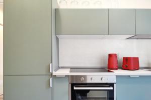 a kitchen with white cabinets and red appliances at Otto Violini - City Center in Cremona