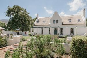 an exterior view of a white house with a garden at Rickety Bridge Estate in Franschhoek