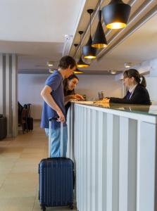 a man standing at a counter with a suitcase at Park Hotel Porto Valongo in Valongo