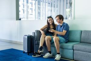 a man and woman sitting on a couch looking at a cell phone at Park Hotel Porto Valongo in Valongo