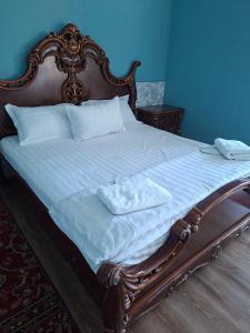 a bed with a wooden frame with two towels on it at Ramzan Family Guest House in Samarkand
