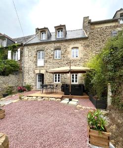 a stone house with a patio and a table at La Vallée d'émeraude in Plouër-sur-Rance