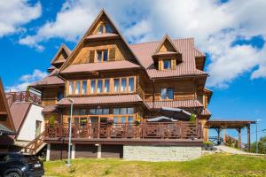 a large wooden house with a roof at HOTEL*** NAT Bukowina Tatrzańska in Bukowina Tatrzańska