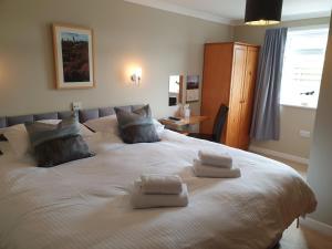 a bedroom with a large white bed with towels on it at Bellavista Guest House in Kirkwall
