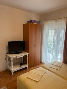 a bedroom with a bed and a television and a cabinet at Apartmani Palma in Sutomore