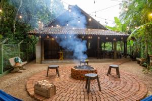 a brick patio with a fire pit in front of a house at Sítio Temporada in Guabiruba