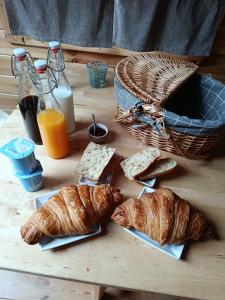 a table with bread and croissants and a basket of milk at Auvergne Kota in Brugheas