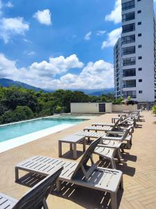 a row of wooden benches sitting next to a swimming pool at Apartamento Armenia in Armenia