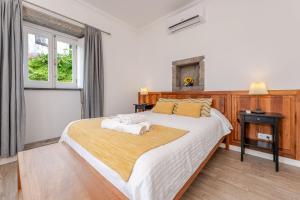 a bedroom with a large bed with two towels on it at Casas do Forneiro - T1 in Nordeste +21 photos
