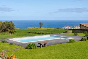 a swimming pool with a bench and the ocean at Casas do Forneiro - T1 in Nordeste