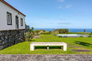 a bench sitting in the grass next to a building at Casas do Forneiro - T1 in Nordeste