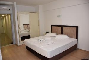 um quarto com uma cama com lençóis brancos e um espelho em Beyazköşk Otel em Istambul