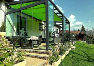 a green house with glass doors and some plants at Cazare Colibita - Casa Lipan cu jacuzzi, foișor și loc de joacă in Colibiţa
