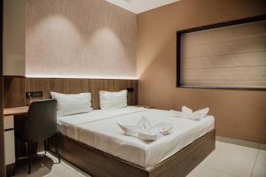 a bedroom with a bed with a desk and a chair at Varanashi Inn in Tiruppūr