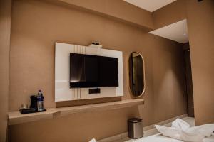 a bathroom with a tv and a mirror at Varanashi Inn in Tiruppūr