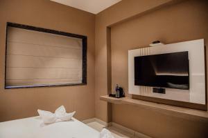 a hotel room with a television and a bed with at Varanashi Inn in Tiruppūr