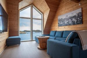 a living room with a blue couch and a large window at Henningsvær Rorbuer in Henningsvær
