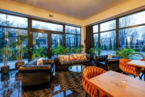 a living room with leather furniture and large windows at Hotel Południk Park Conference&SPA in Stargard