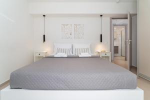 a white bedroom with a large bed and two tables at M P A Luxury Apartment Α2 in Agios Nikolaos