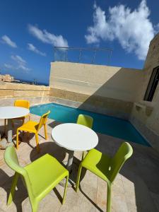 a patio with tables and chairs and a pool at Serenity Wellness Farmhouse With Private Sauna in Nadur