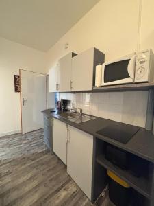 a kitchen with white cabinets and a microwave at Ferienwohnung Maks und Kris in Sankt Andrä bei Frauenkirchen
