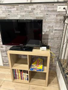 a television on a wooden stand in front of a brick wall at Chez nathalie in Habay-la-Neuve