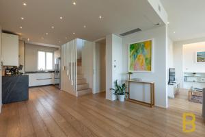 a large kitchen and living room with a wooden floor at BePlace Apartments Arona in Arona