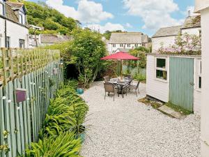 a patio with a table with an umbrella and a fence at 3 Bed in Looe oc-92273 in Polperro