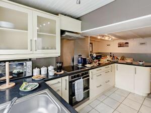 a large kitchen with white cabinets and a sink at 3 Bed in Looe oc-92273 in Polperro +17 photos