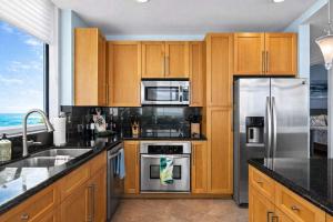a kitchen with wooden cabinets and stainless steel appliances at Sapphire Beach - Breathtaking 26th Floor Views in South Padre Island