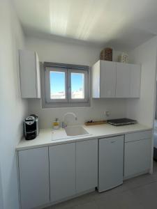 a kitchen with white cabinets and a sink and a window at CHORA NEST KYTHNOS in Kithnos +16 photos