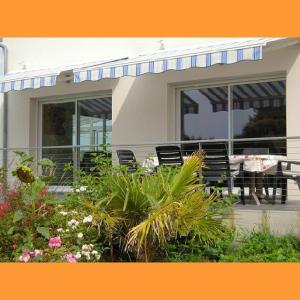 a house with a table and chairs and flowers at Le Pic-Vert in Rang-du-Fliers