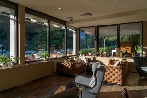 a living room with couches and chairs and large windows at Hotel Kranjska Gora in Kranjska Gora
