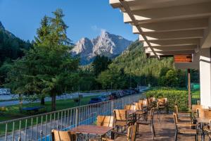a balcony with tables and chairs and a view of a mountain at Hotel Kranjska Gora in Kranjska Gora +140 photos