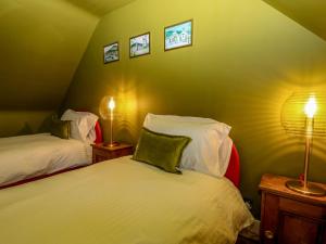 a bedroom with two beds and two lamps on the wall at Lindean in Ballater