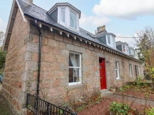 an old brick house with a red door at Lindean in Ballater