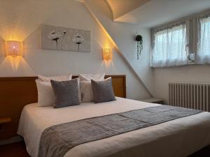 a bedroom with a large bed with white pillows at Hôtel Deybach in Munster