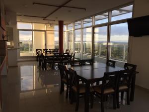una sala da pranzo con tavoli e sedie e grandi finestre di Apartamento Acapulco Roosevelt a Punta del Este