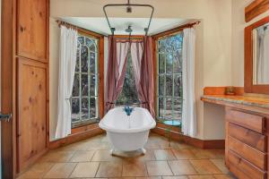 a bathroom with a white bath tub in front of windows at The Cabin at Rooster Ridge in Fischer