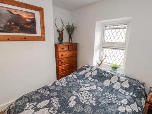 a bedroom with a bed and a dresser and a window at 25 Low Seaton in Workington